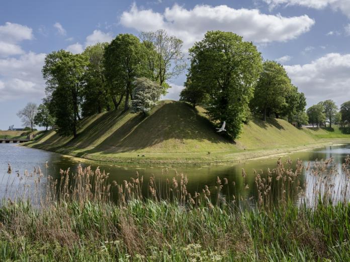 Græsklædte skåninger, store træer og voldgrav på Kastellet.