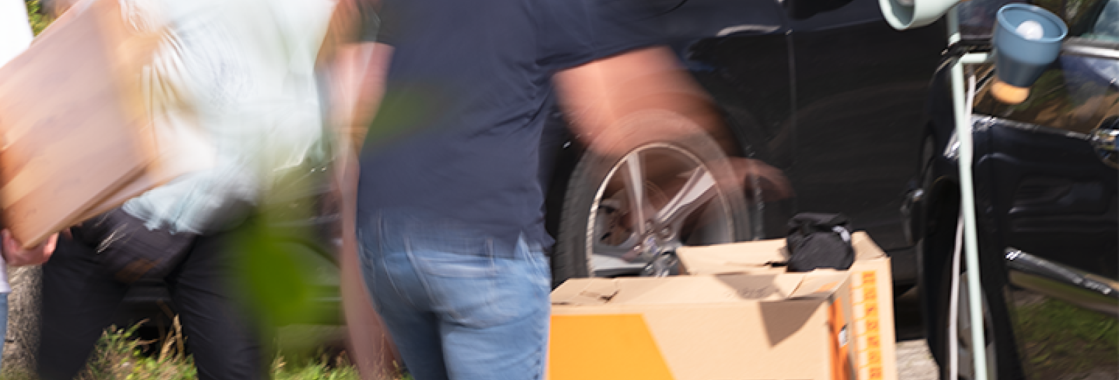 Mennesker der bærer flyttekasser ud af en bil 