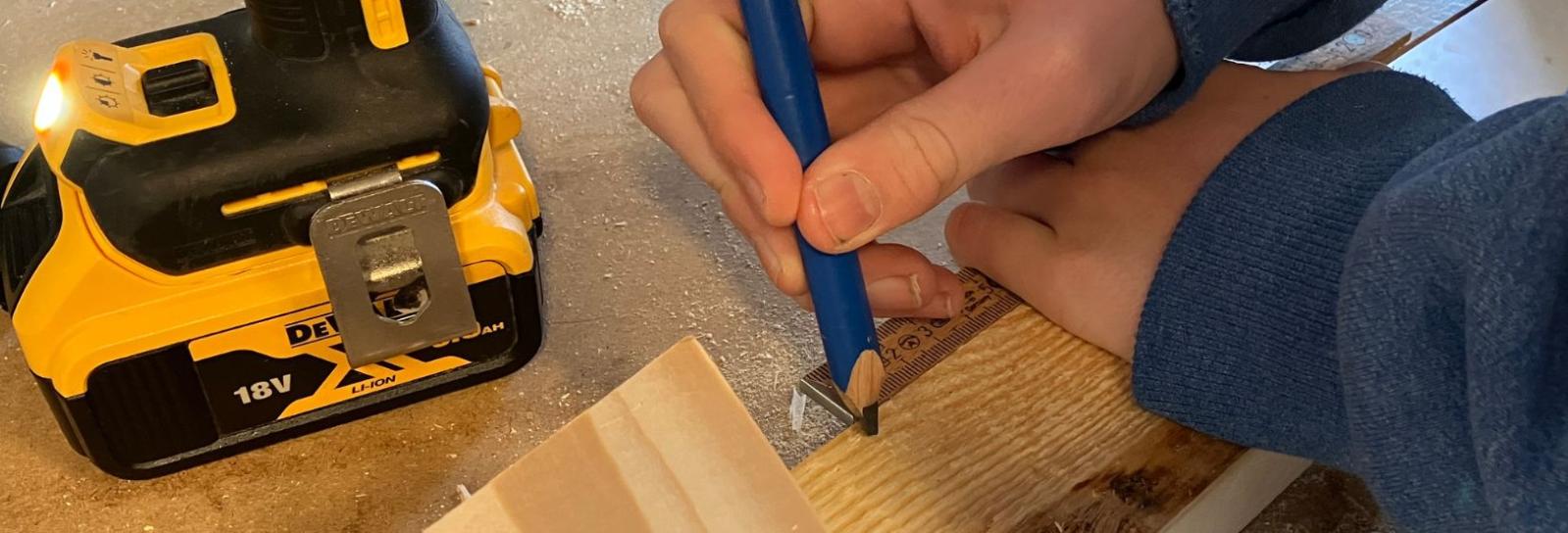 En elev tegner måler op og tegner på et stykke træ